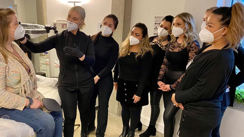 Permanent makeup instructor demonstrating brow mapping for a group of students