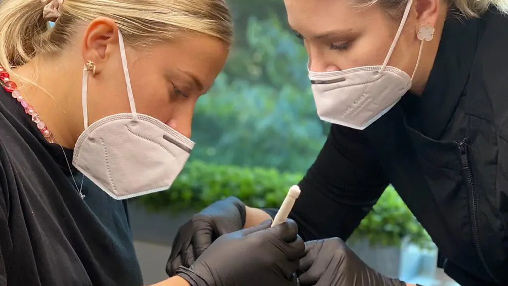 Two permanent makeup artists practicing technique together during live training