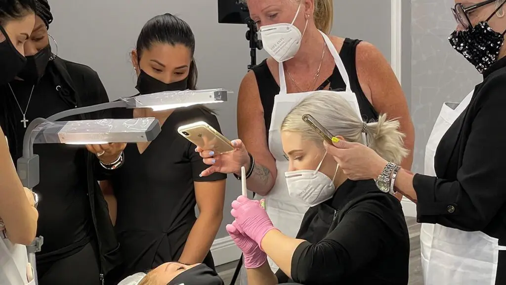 Permanent makeup student working on a live model with instructors observing