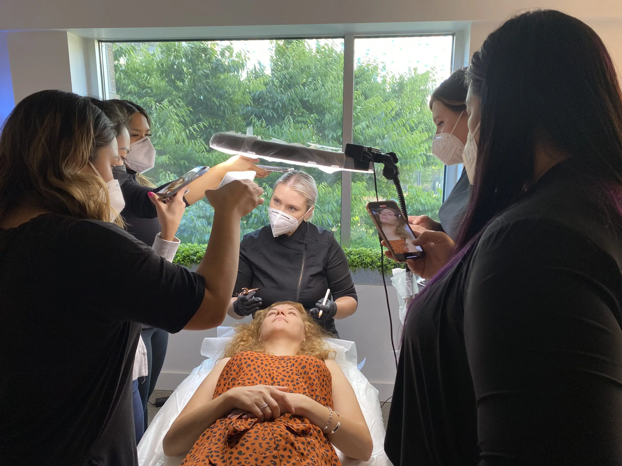 Beauty Angels Academy class gathered around a live model demonstration