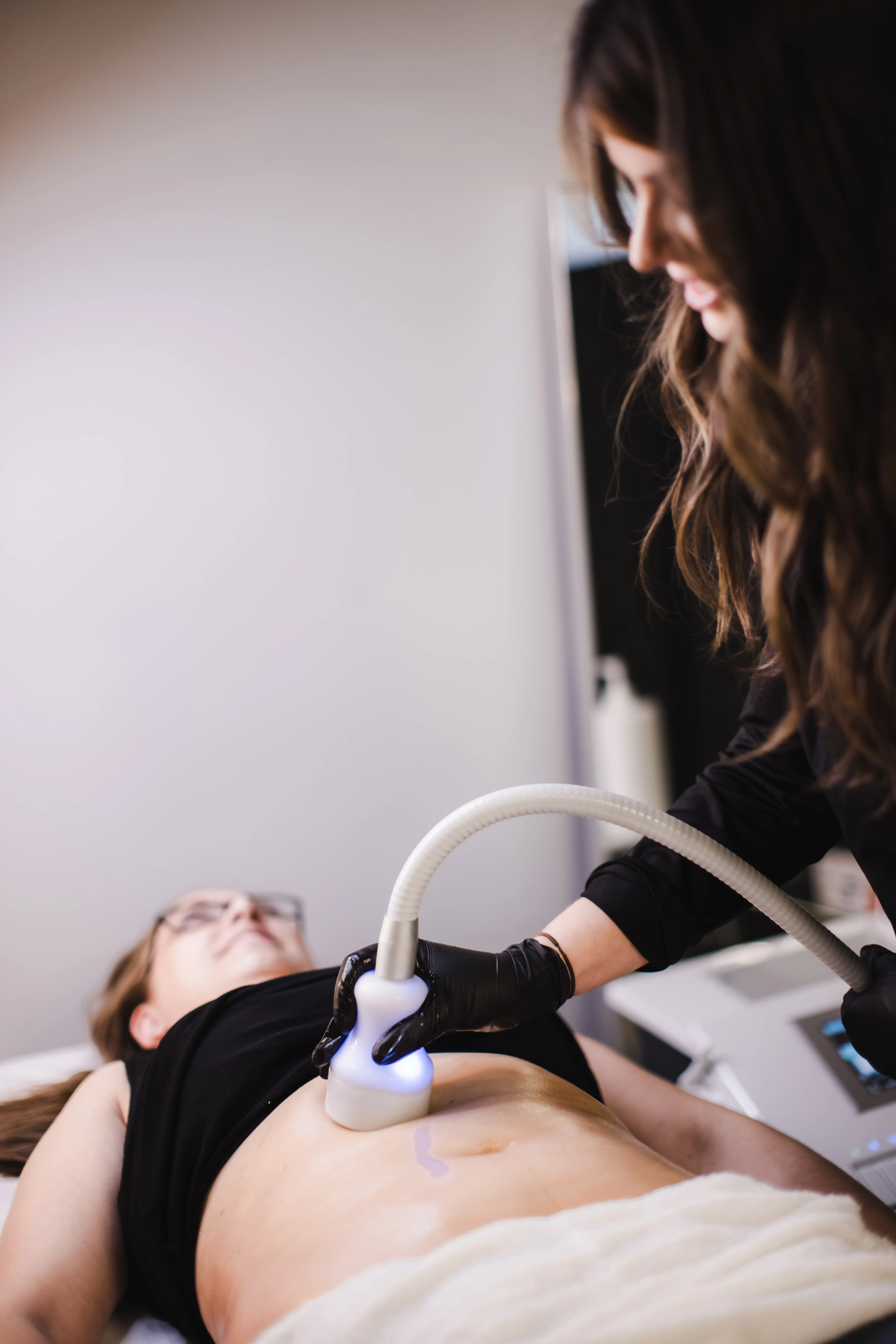 Body sculpting technician performing a cryo treatment on a client's abdomen