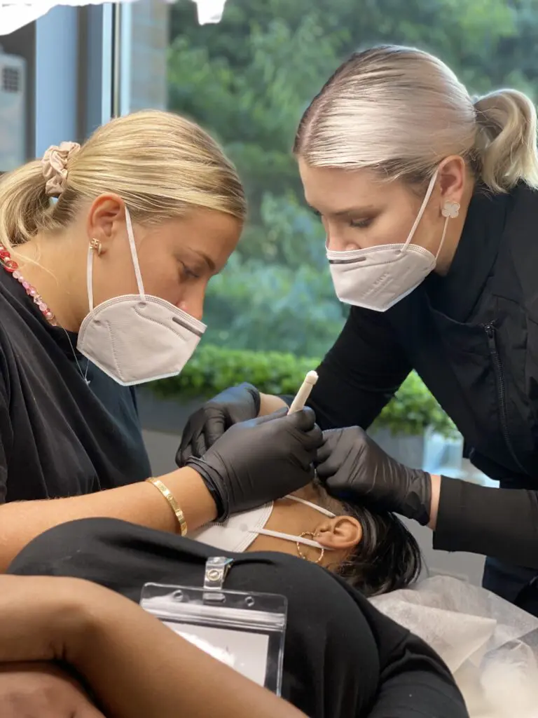 Permanent makeup instructors teaching a student on a live model
