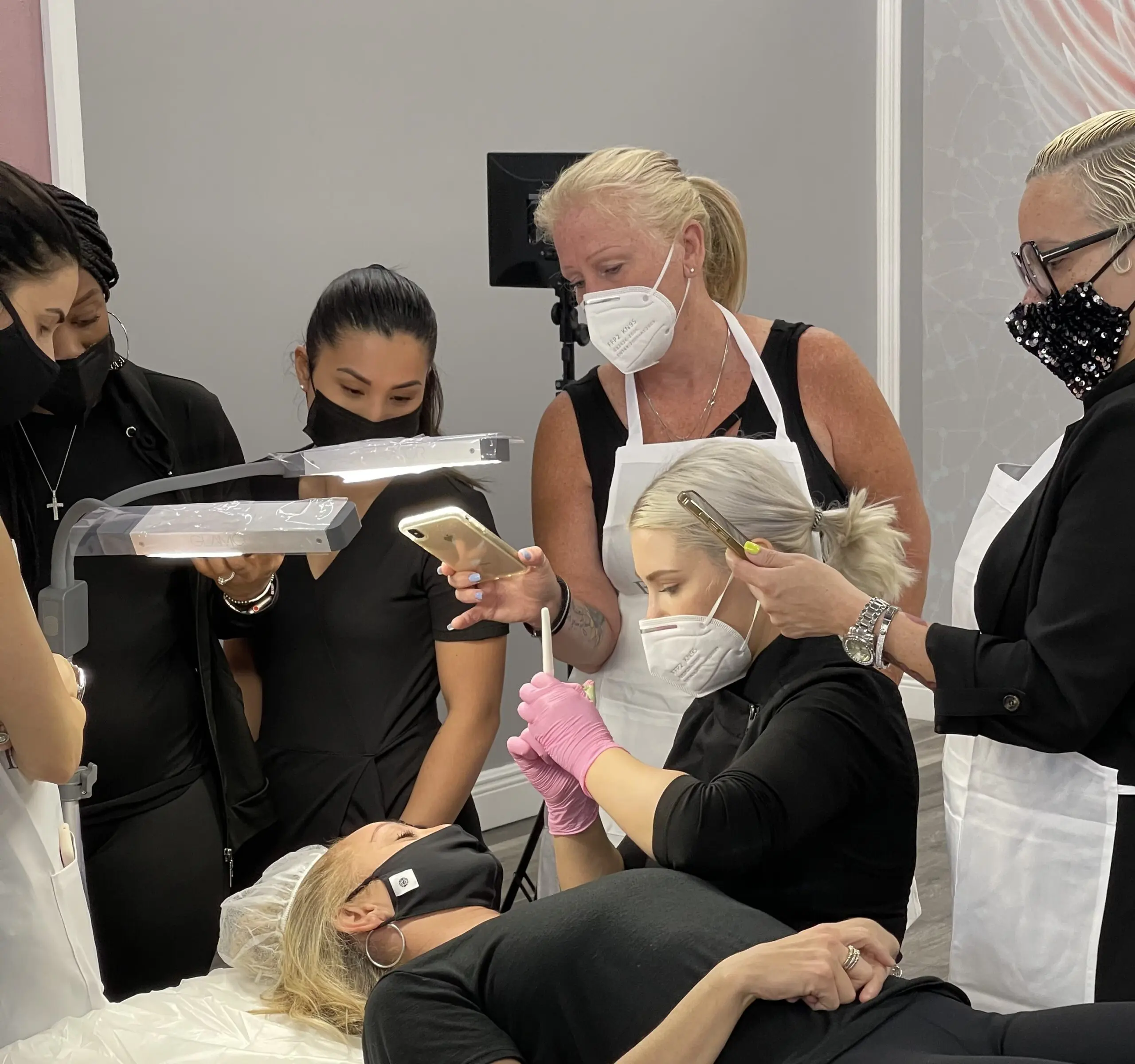 Permanent makeup students practicing on a live model with an instructor